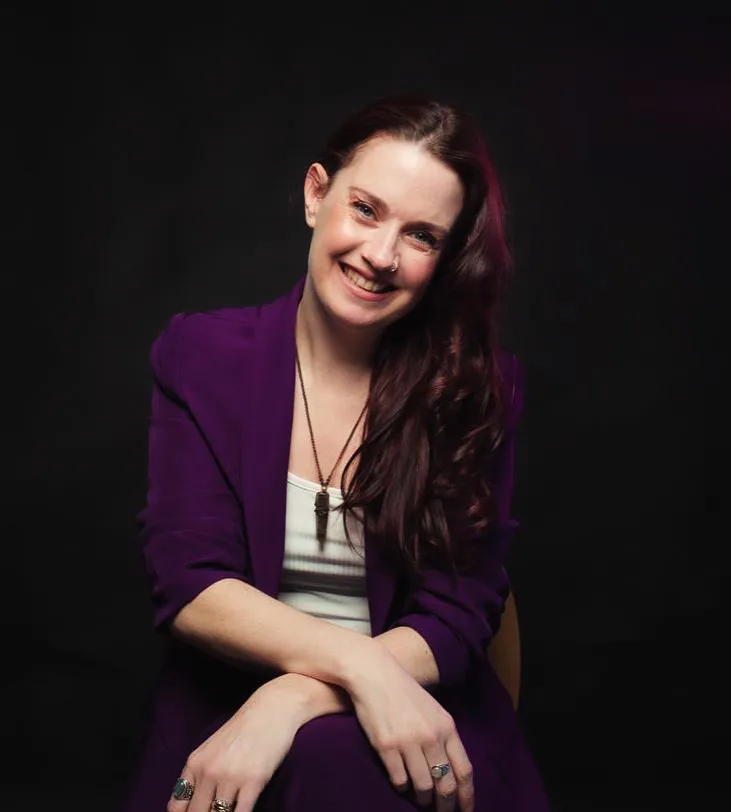 Jo, founder of Indigo Life, seated in a purple suit