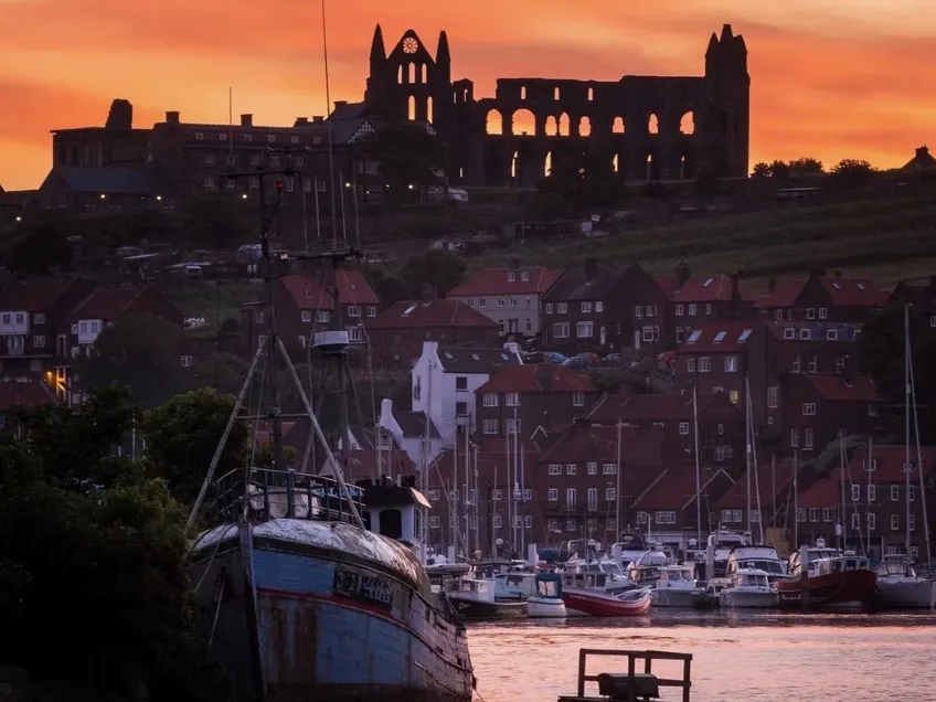 Whitby Abbey above the harbour at sunset