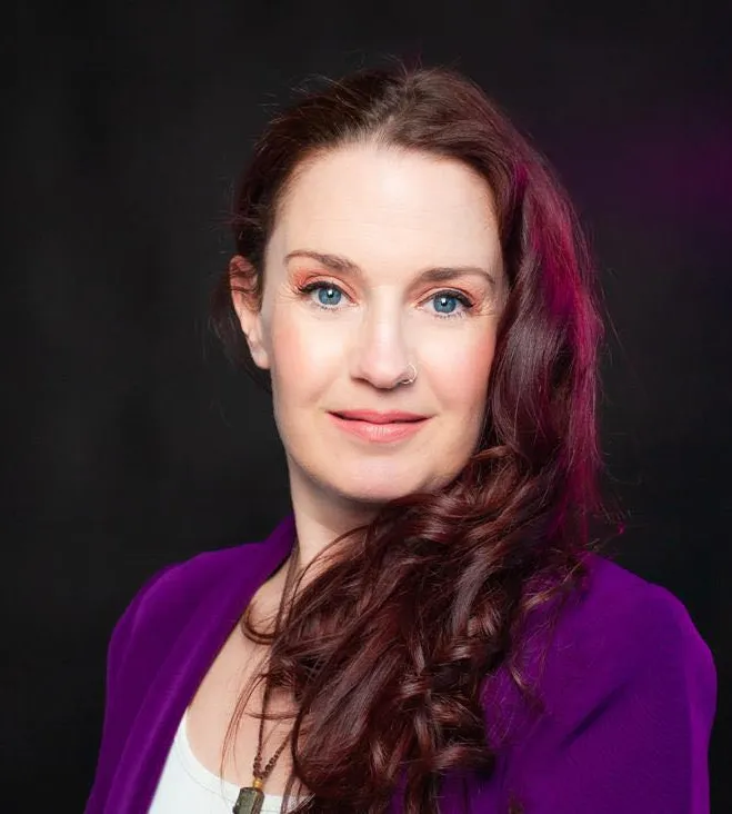 Jo smiling, wearing a purple suit